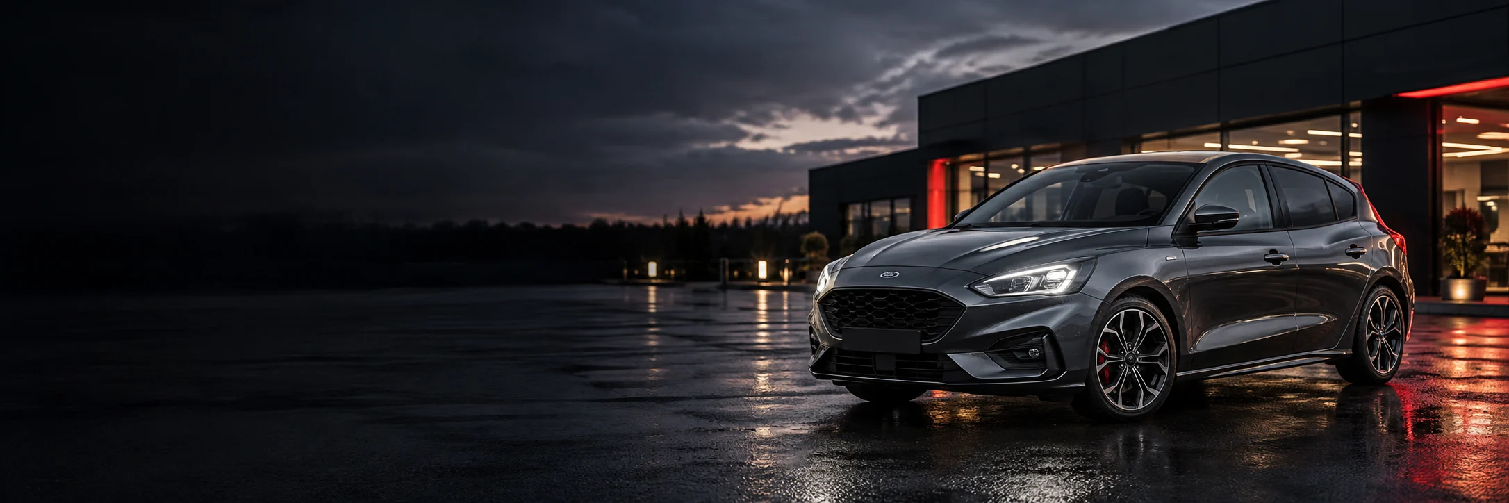 Grey hatchback outside a showroom at dusk